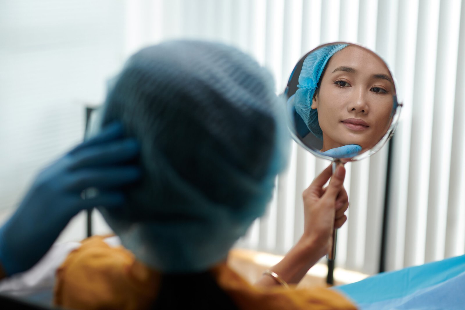 Young Asian woman looking at mirror after getting beauty treatment in clinic